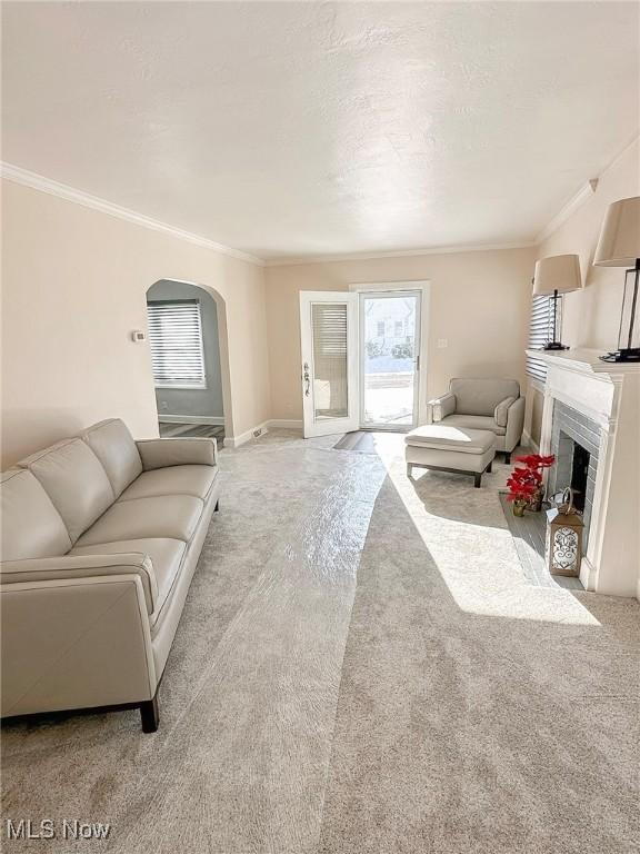 carpeted living room with crown molding and a fireplace