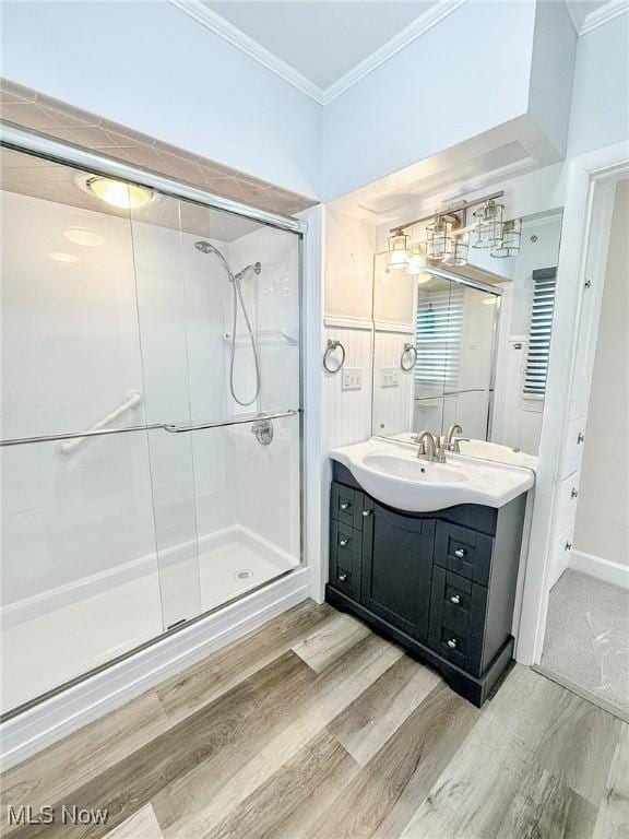 bathroom with wood-type flooring, vanity, a shower with door, and crown molding