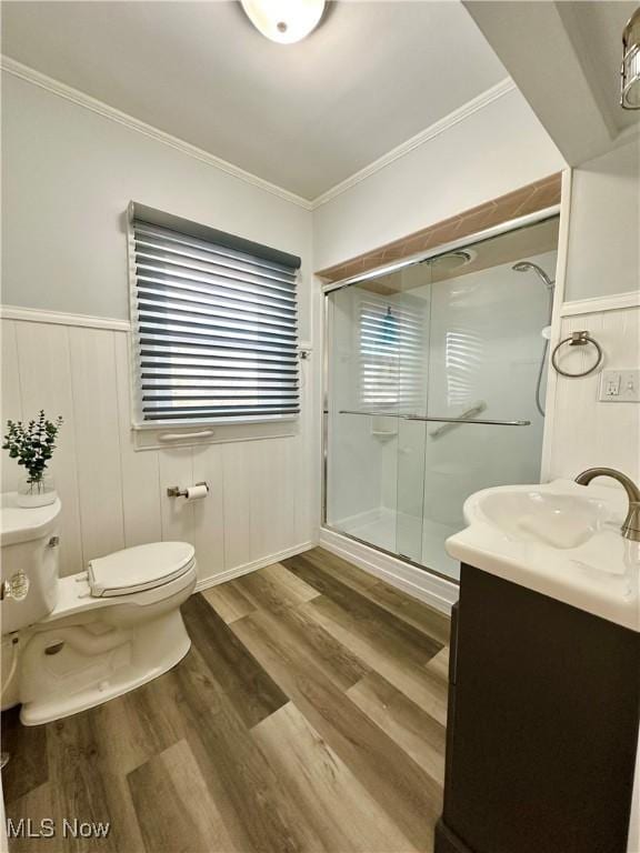 bathroom with ornamental molding, vanity, a shower with door, hardwood / wood-style flooring, and toilet