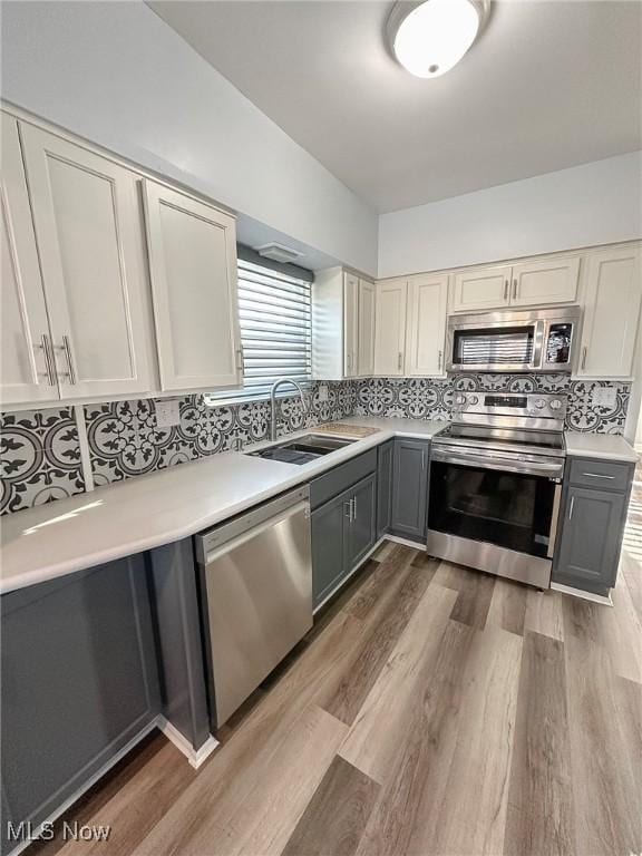 kitchen with wood-type flooring, stainless steel appliances, gray cabinetry, and sink