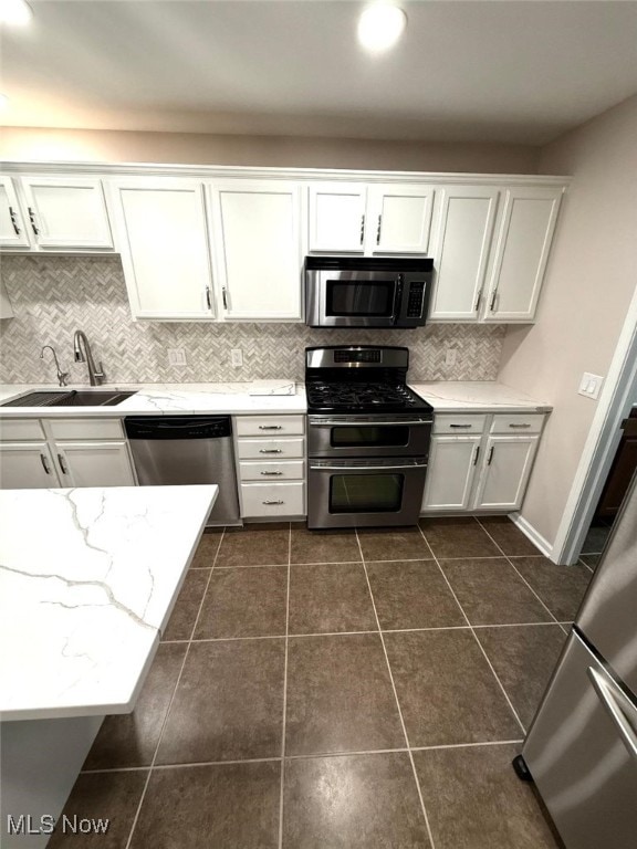 kitchen with white cabinetry, sink, dark tile patterned flooring, and appliances with stainless steel finishes