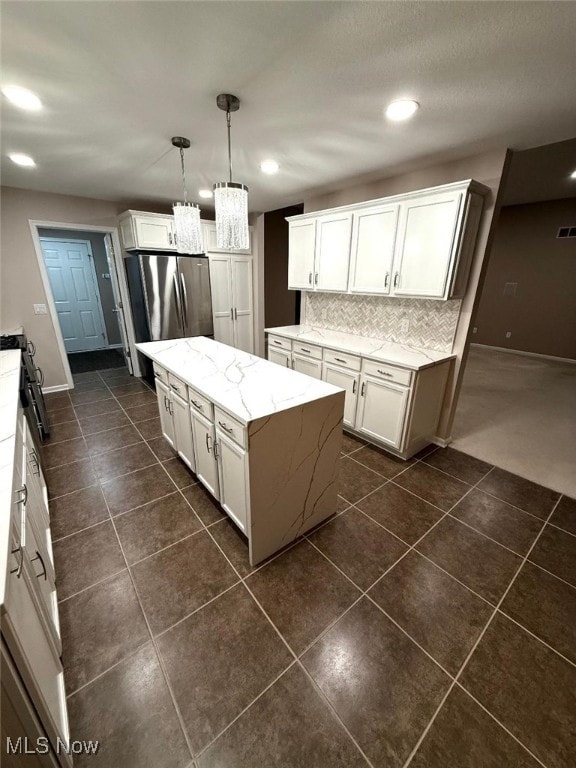 kitchen featuring decorative backsplash, pendant lighting, white cabinets, a center island, and stainless steel refrigerator