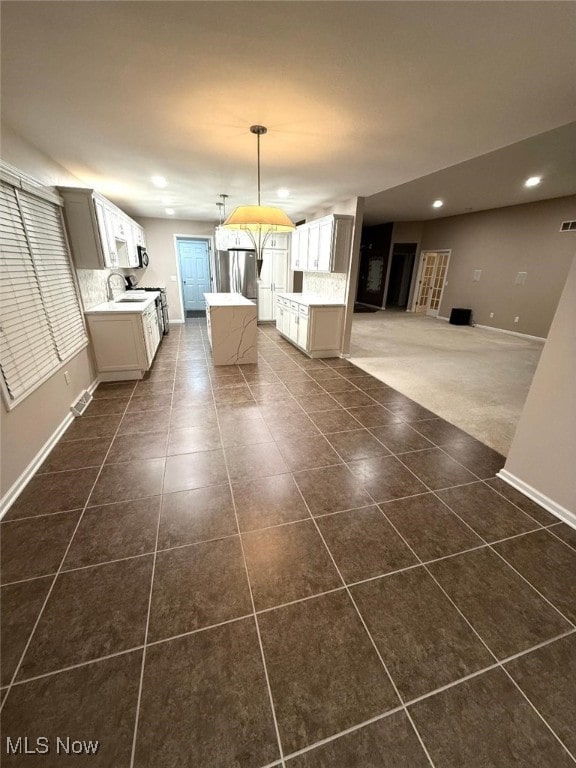 kitchen with decorative backsplash, stainless steel fridge, a center island, and decorative light fixtures