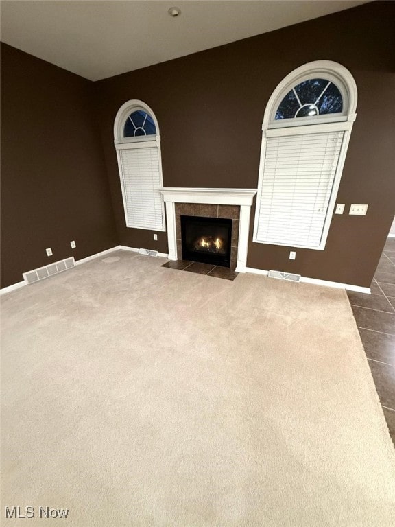 unfurnished living room with a fireplace and dark colored carpet