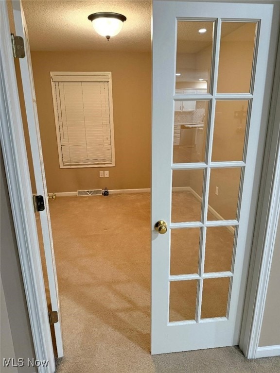 hall with carpet floors and a textured ceiling