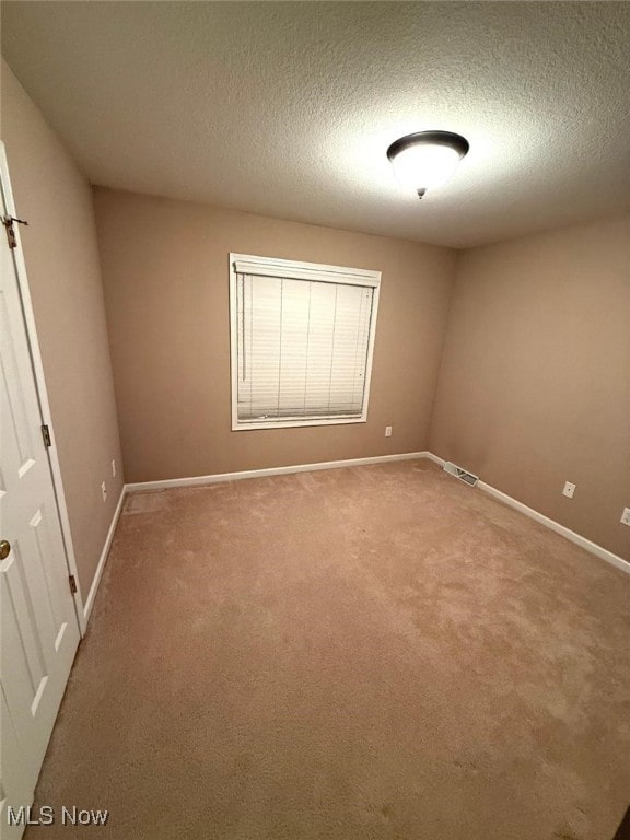 carpeted empty room with a textured ceiling