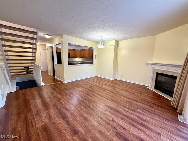 unfurnished living room with wood-type flooring and a textured ceiling