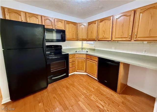 kitchen featuring a textured ceiling, light hardwood / wood-style floors, backsplash, and black appliances