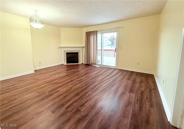 unfurnished living room featuring dark wood-type flooring and a textured ceiling