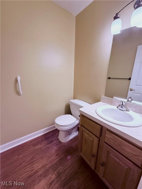 bathroom with toilet, vanity, wood-type flooring, and a textured ceiling