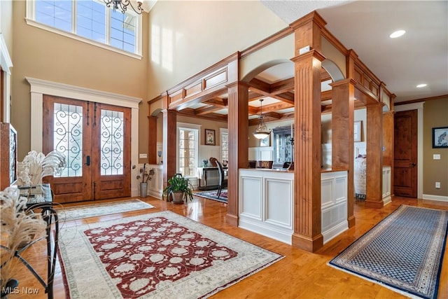 entryway with light wood-type flooring, ornate columns, a wealth of natural light, and french doors