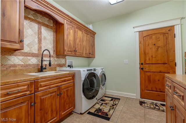 clothes washing area featuring cabinets, a textured ceiling, sink, light tile patterned floors, and independent washer and dryer