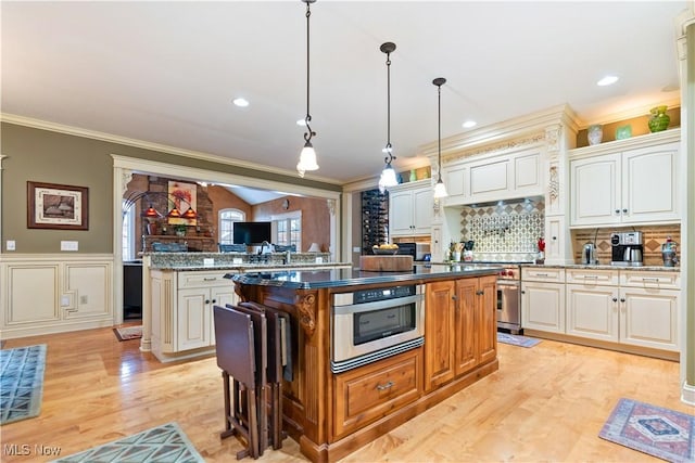 kitchen with white cabinets, decorative light fixtures, a center island, and dark stone countertops