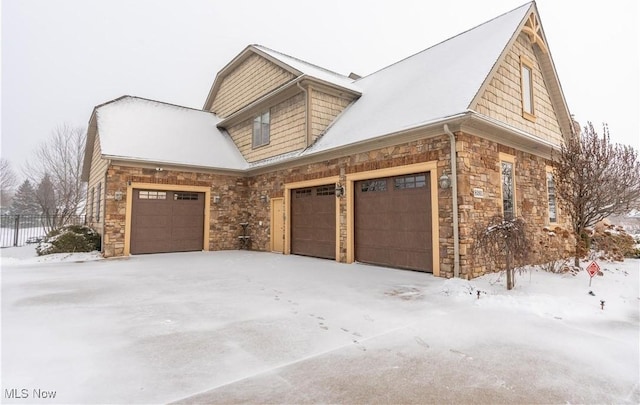 snow covered property with a garage