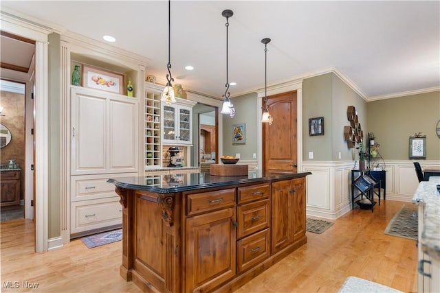 kitchen with a center island, ornamental molding, decorative light fixtures, light hardwood / wood-style floors, and a kitchen bar