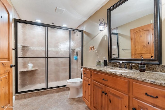 bathroom featuring tile patterned floors, toilet, vanity, and walk in shower