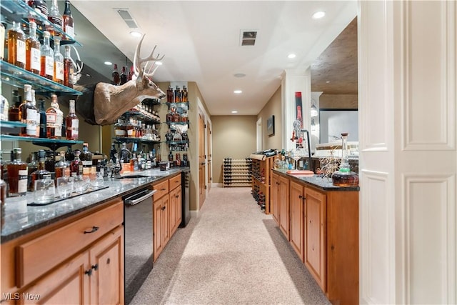 bar with black dishwasher, dark stone countertops, sink, and light carpet