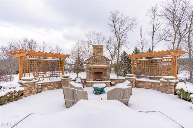 snow covered patio featuring an outdoor stone fireplace and a pergola