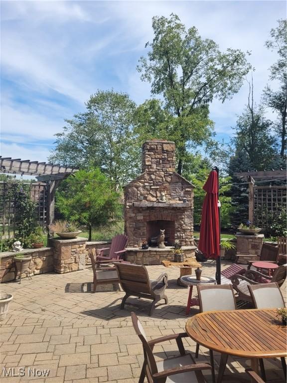 view of patio featuring an outdoor stone fireplace and a pergola