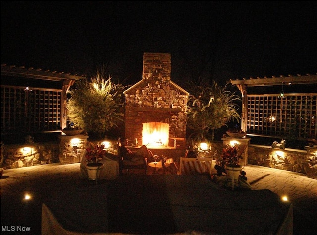 yard at night featuring an outdoor stone fireplace and a patio