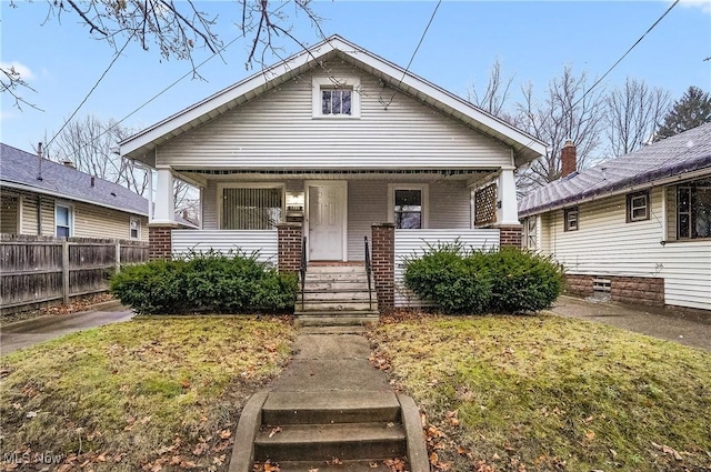 bungalow-style house featuring covered porch and a front yard