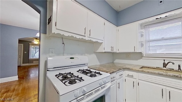 kitchen featuring white cabinetry, white gas stove, ceiling fan, dark wood-type flooring, and sink