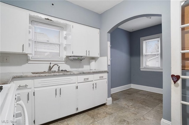 kitchen featuring range, white cabinetry, and sink