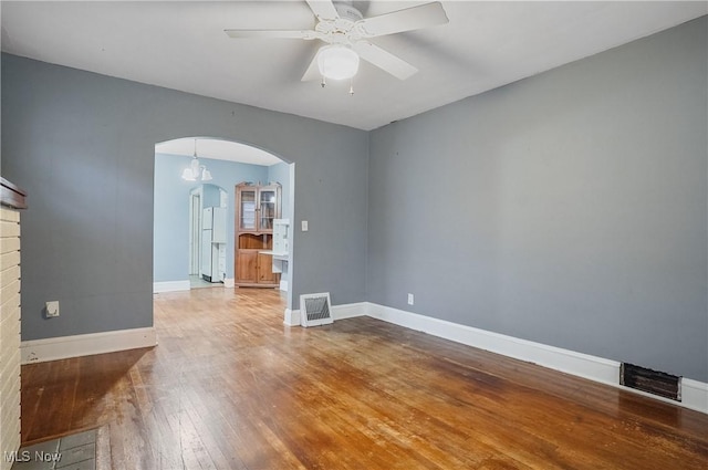 unfurnished room with a brick fireplace, ceiling fan, and hardwood / wood-style flooring