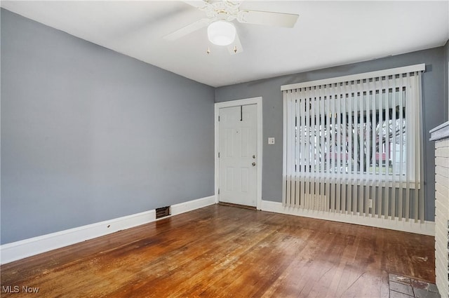 unfurnished room with ceiling fan, hardwood / wood-style floors, and a brick fireplace