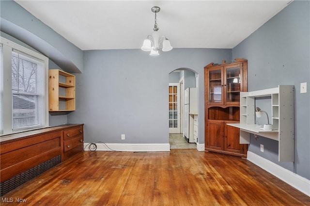 unfurnished dining area with hardwood / wood-style floors and an inviting chandelier