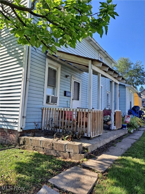 doorway to property featuring a porch and cooling unit