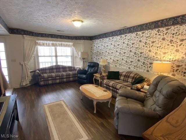 living room featuring dark wood-style flooring, a healthy amount of sunlight, a textured ceiling, and wallpapered walls