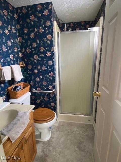 bathroom featuring toilet, a textured ceiling, a shower stall, and wallpapered walls