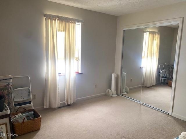 unfurnished bedroom with carpet, a closet, baseboards, and a textured ceiling