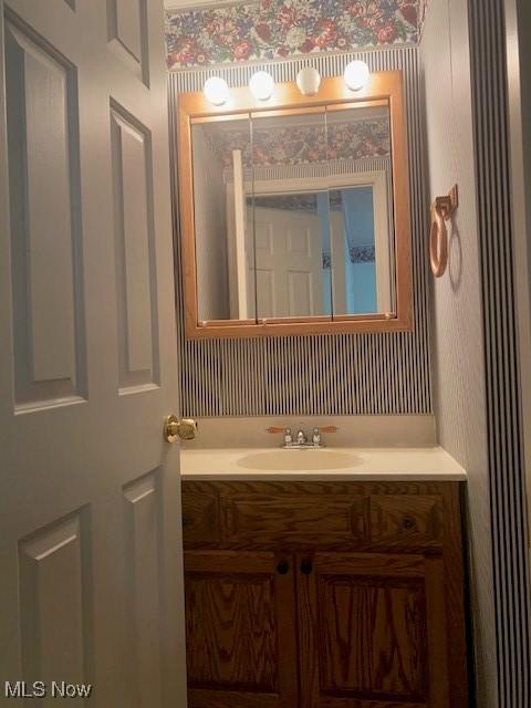 bathroom with vanity and wallpapered walls