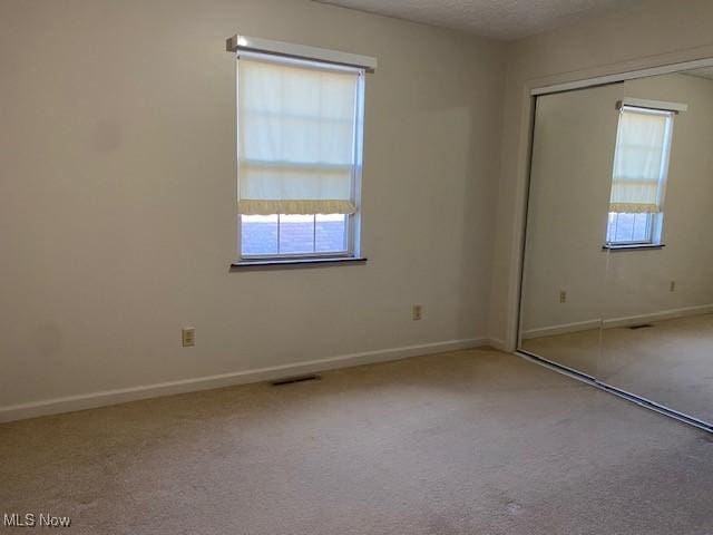 empty room featuring a textured ceiling, baseboards, visible vents, and carpet floors