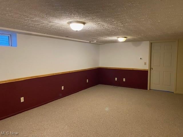 finished below grade area featuring carpet and a textured ceiling