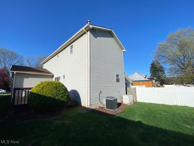 view of property exterior with a yard, fence, and central AC