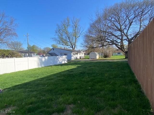 view of yard with a storage shed, fence, and an outbuilding