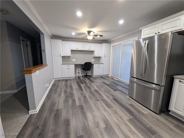 kitchen featuring white cabinets, stainless steel fridge, built in desk, and decorative backsplash