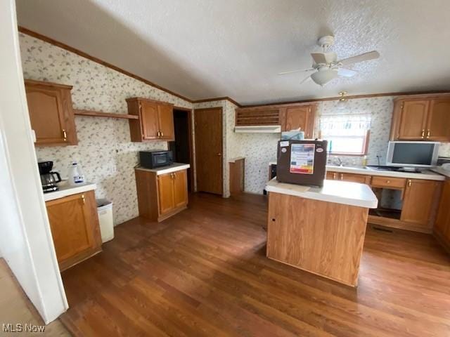 kitchen with ornamental molding, a textured ceiling, ceiling fan, hardwood / wood-style floors, and a center island