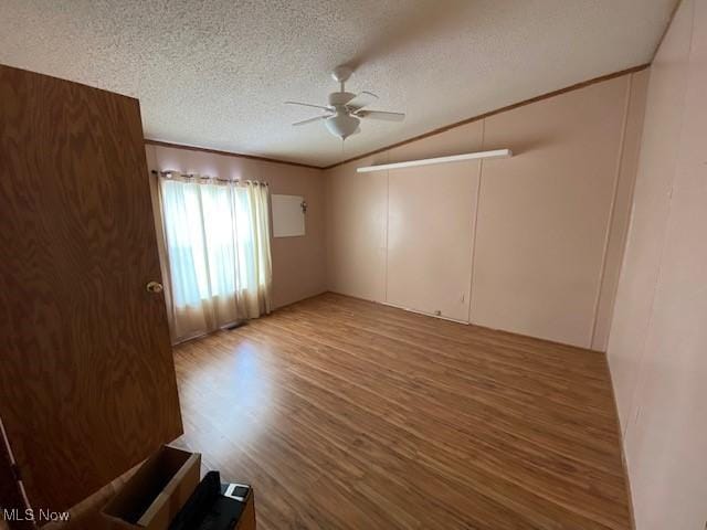 empty room featuring lofted ceiling, ceiling fan, wood-type flooring, and a textured ceiling