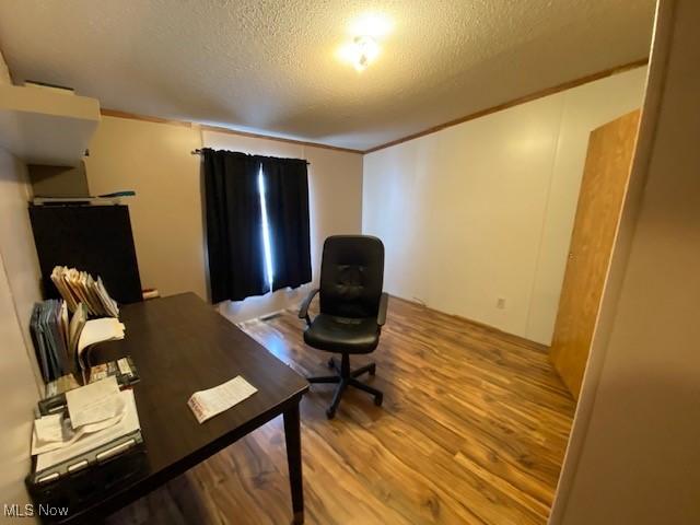 home office with a textured ceiling and light hardwood / wood-style flooring