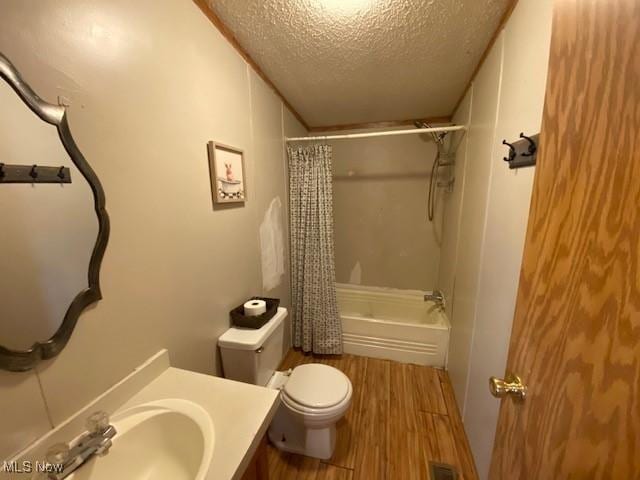 full bathroom with wood-type flooring, a textured ceiling, toilet, vanity, and shower / tub combo