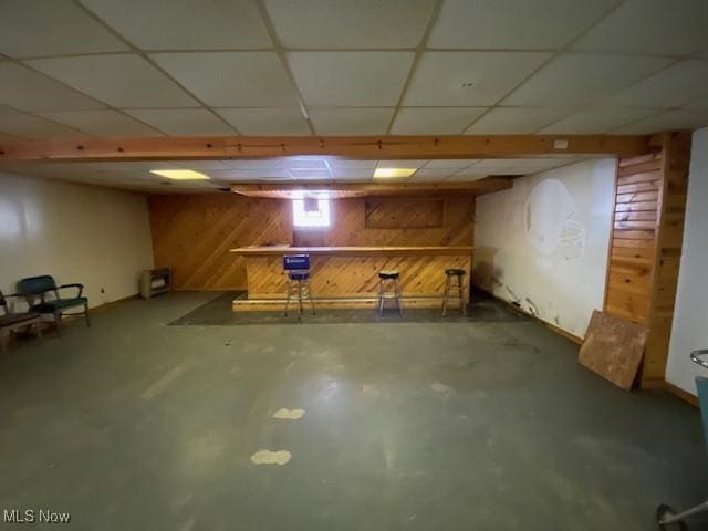 basement featuring a paneled ceiling and wooden walls