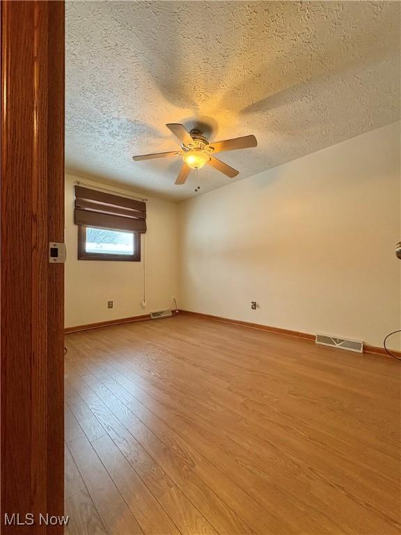 unfurnished room with ceiling fan, light hardwood / wood-style floors, and a textured ceiling