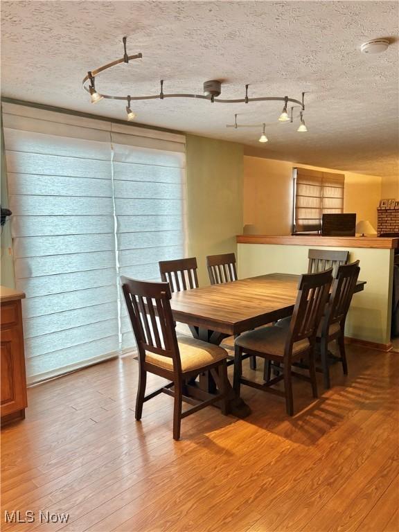 dining room with hardwood / wood-style floors and a textured ceiling