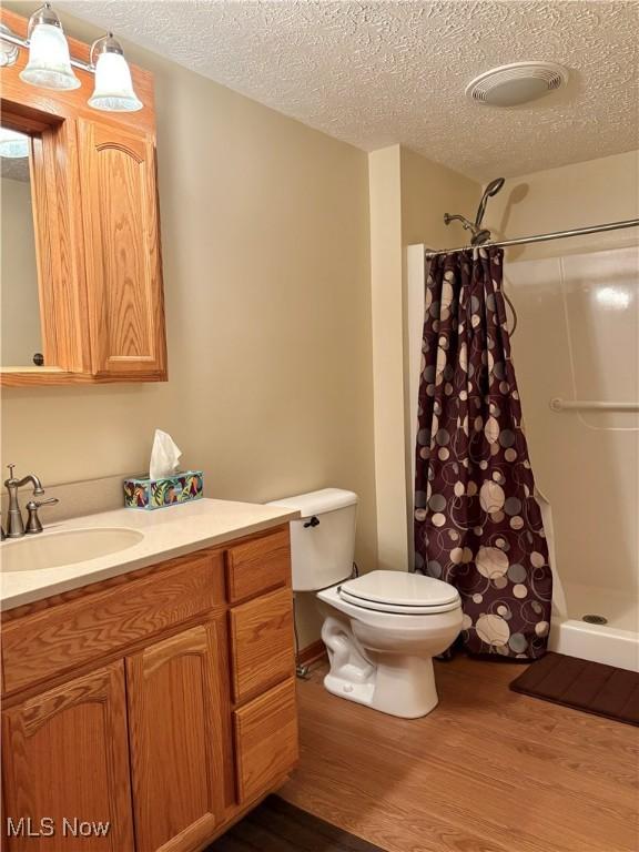 bathroom featuring vanity, wood-type flooring, a textured ceiling, and walk in shower