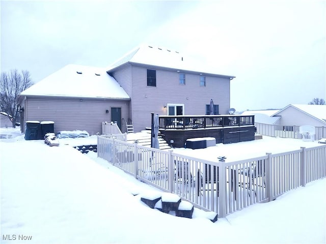 snow covered back of property featuring a wooden deck