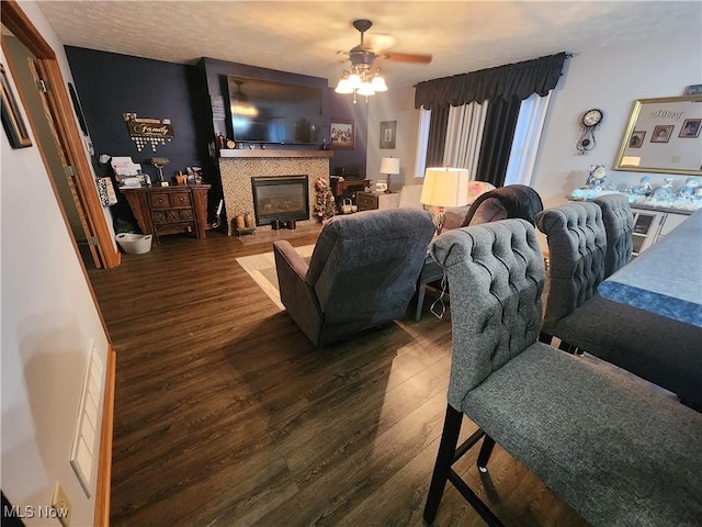 living room with a tiled fireplace, ceiling fan, and dark hardwood / wood-style flooring